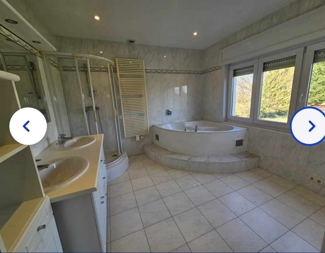 Grande salle de bain en marbre avec baignoire jacuzzi d'angle et double vasque